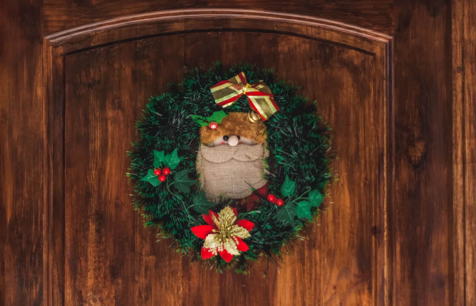 An evergreen wreath hanging on a wooden front door